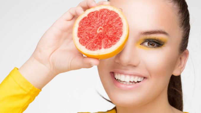 Young brunette with red grapefruit in her hand